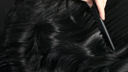 Closeup black hair texture, slow motion of female hand combing long curly hair - Powered by Adobe