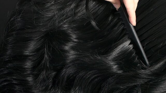 Closeup black hair texture, slow motion of female hand combing long curly hair