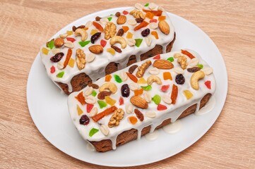 Delicious fruitcake with nuts and icing on a white plate, close-up shot