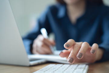Close up business woman working, using calculator to calculate budget  and tax with laptop computer...