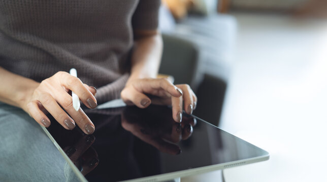 Close up, business woman in casual clothes, using digital tablet with stylus pen, working at home. Graphic designer working on design project, finger touching on screen, freelance lifestyle - Powered by Adobe