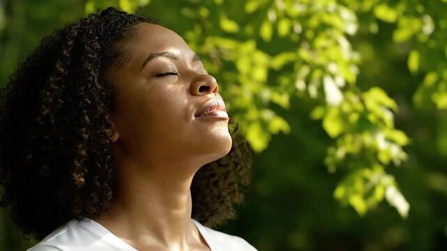 Woman Meditating with Eyes Closed in Nature Sunlight with Green Leaves Background and Soft Lighting for Relaxation and Spiritual Concept Stock Footage Video Optimized for Adobe