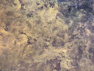 Close up of antique gold metallic washed decorative paint. Dark gold limestone washed textured paint, with abstract grunge and dirt pattern. Seamless background texture.