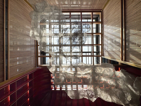 Unique cloud wiremesh artwork structure as a ceiling and hanging lamp chandelier decoration on a high void leading to architectural skylight above.