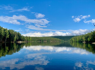Scenic view of Nøklevann Lake near Oslo on a clear summer day. Calm water reflects the blue sky and green forest.