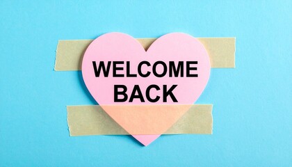 Pink heart cutout with “WELCOME BACK” taped to blue background.