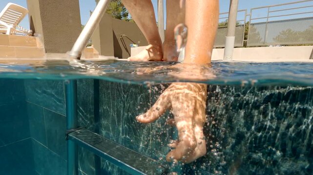 Woman drops mobile phone into water in swimming pool and tries to catch smartphone with hand