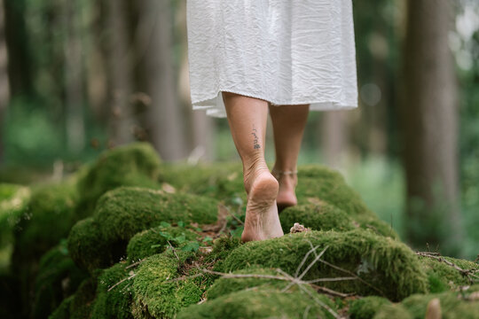 Natural close-up of female feet walking barefoot on mossy ground in a quiet forest atmosphere
