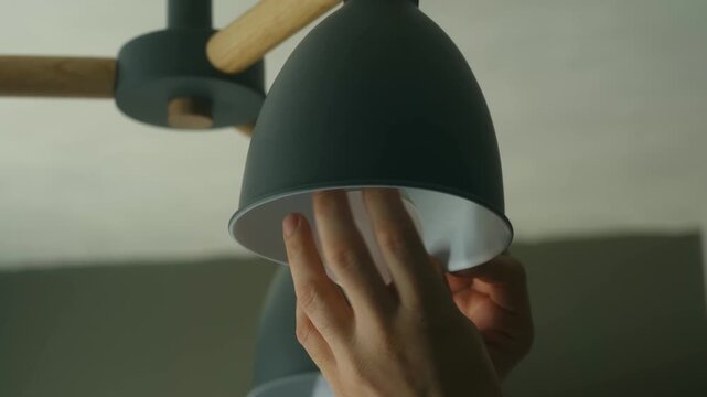 Handyman hands screwing an energy efficient led light bulb into a modern ceiling lamp fixture. Home improvement and maintenance concept for saving electricity and repairing equipment