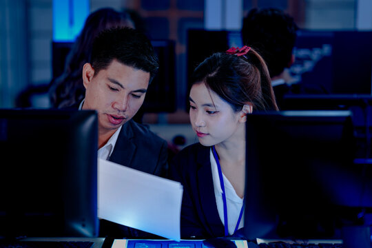 Diverse tech professionals collaborating intensely. Focused team synergy, reviewing project data side-by-side in a modern, blue-lit command center workspace.