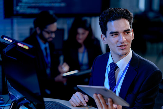 A data analyst scrolls through complex visualizations on a tablet comparing results against code displayed onscreen working late to finalize a critical business intelligence report.