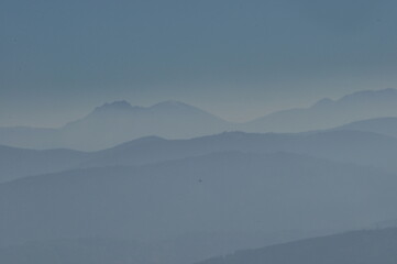 Distant mountain ranges shrouded in soft blue haze at dawn, creating a serene landscape