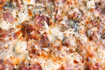 Pizza with melted cheese, ham, and herbs