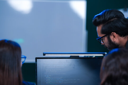 Deep code analysis huddle late night. Senior developer points out intricate logic colleague absorbs critical details screen reflects complex script intense debugging session proceeds now code work.