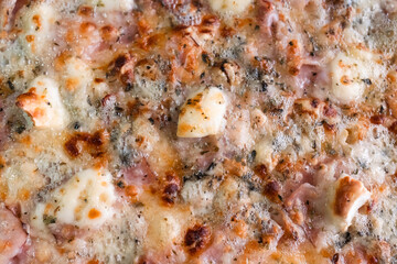 Pizza with melting cheese, ham, and herbs close-up