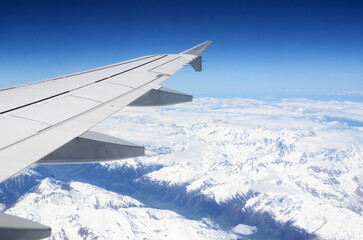 Obraz premium View from an airplane window flying over snowy alps mountains