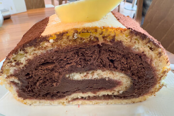 Chocolate swiss roll cake with creamy filling and white chocolate garnish on a plate