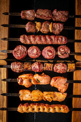 Tender beef and chicken skewers are neatly arranged for grilling in the dim light