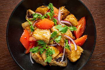 Colorful mix of fried tofu, tomatoes, and onions topped with sesame and cilantro