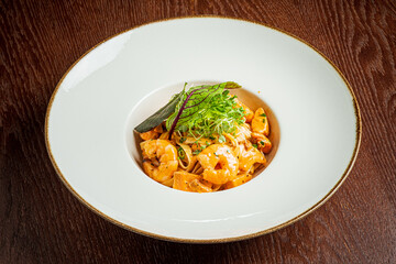 Tantalizing shrimp pasta dish beautifully arranged with vibrant green herbs on a dark wooden table