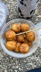 Spicy Indonesian street food bakso aci served in a paper bowl with lime, cabbage, and chili toppings