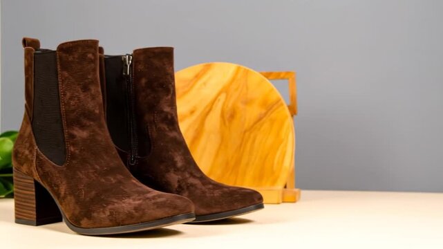 A pair of brown suede ankle boots with a zipper, wooden heels, and a textured elastic panel