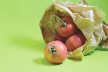 Small, fresh, and healthy tomatoes in a paper bag with a green background.