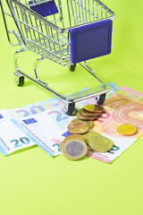 Euro coins and banknotes, green background, copy space. Vertical, close up shot.