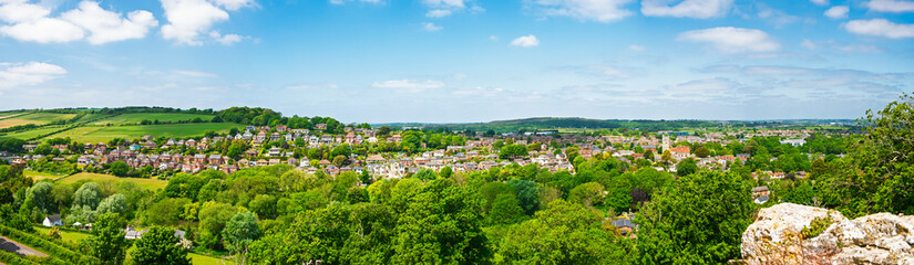 Aerial view over an english rural countryside village amongst trees with panoramic scenery...