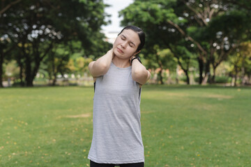 Fototapeta premium women suffering from neck pain while standing outdoors, touching her neck with both hands. Concept for muscle stiffness, poor posture, stress or injury after physical activity.