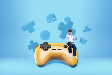 Boy sitting on oversized yellow game controller with headphones