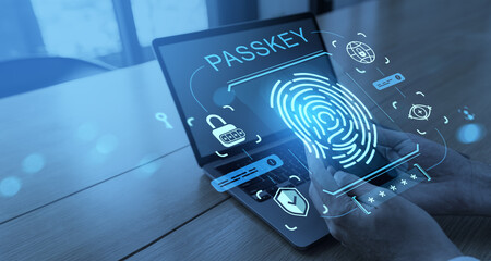 Passkey authentication with fingerprint scanner and digital security icons shown on transparent smartphone over laptop screen in modern office setting.