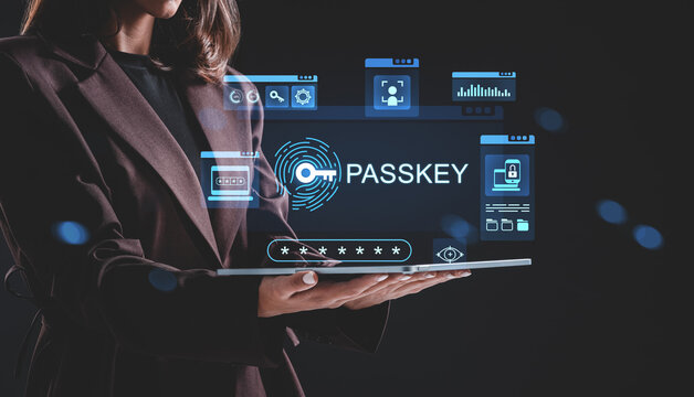 Businesswoman holding tablet projecting hologram with passkey and digital security interface on dark background, illustrating cybersecurity concept.