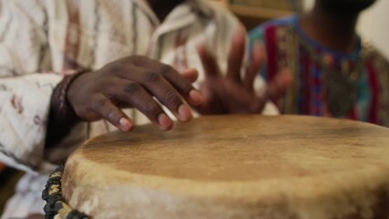 Close-up view of hands of anonymous Black man playing African drum honouring Kwanzaa traditions