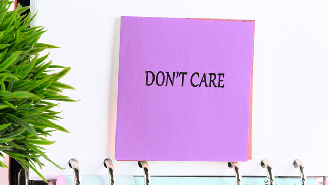 A vibrant purple sticky note featuring the phrase dont care sits prominently on a planner. Lush green plant life adds a fresh touch to the bright workspace