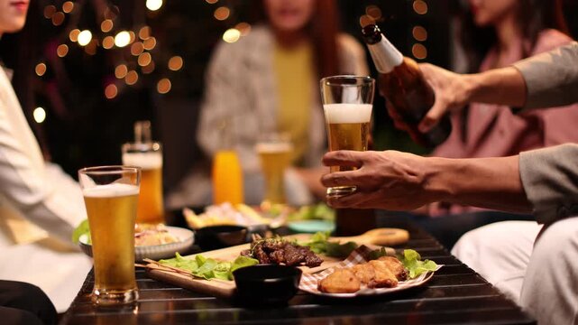 Happy Group of people Asian friends Drinking beer outdoors at the brewery for the New Year festival night time
