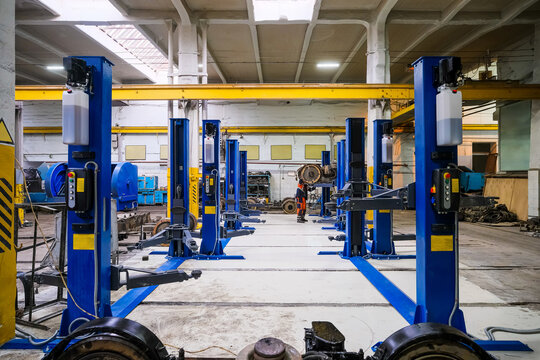 Blue-colored car lifts located in a row in an auto repair shop or garage with several car service stations.