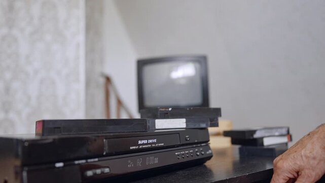 Old-style VHS player on the desk. Male hand presses the button on the device. Close up.