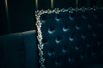 Closeup of a luxurious dark blue velvet headboard with decorative floral accents