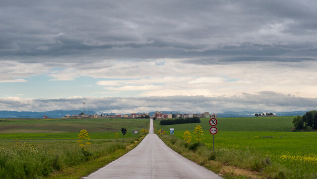 Panorama. Paesaggio di strada che si perde all'infinito in zona rurale tra verdi campi verso antiche case. Puglia, natura Italia.