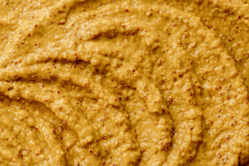Mustard sauce with grains close-up. Hot spices as a background. Texture of Dijon mustard.
