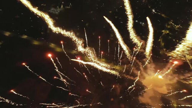 FPV drone flying through exploding fireworks over a ity at night.