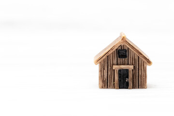 A miniature wooden house model placed on a white background, symbolizing home ownership and mortgage concepts. Ideal for real estate, finance, or housing themes.