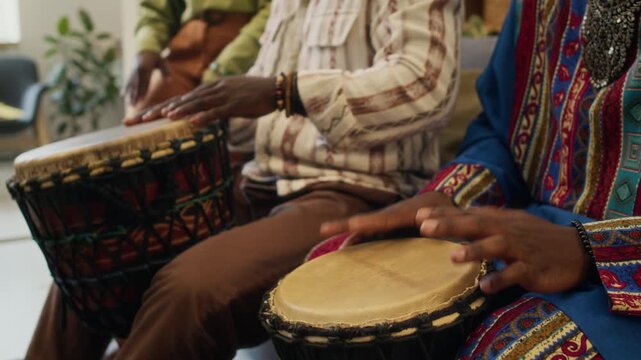 Midsection shot of two unknown Black men playing djembe drums celebrating African identity and culture