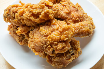 Crispy fried chicken in white plate on wood table