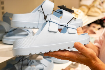 New trendy blue sandals displayed in a retail store with a customer examining them