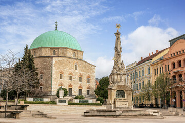 Fototapeta premium Church of the Holy Trinity in Pecs, Hungary, historic building with green dome and stone architecture under blue sky