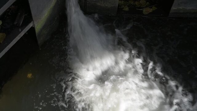 Aerial view of water pouring through the lock gate at Rammey Marsh Lock on the River Lea Navigation, showing movement and canal engineering.