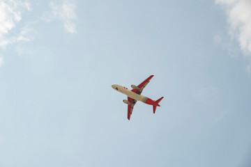 Airplane flying high in a clear sky on a sunny day over a bustling city