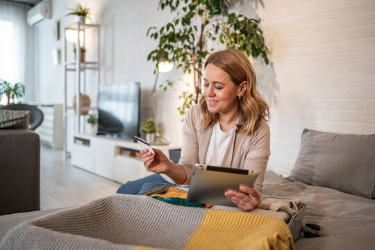 Woman booking travel accomodations online using tablet and credit card